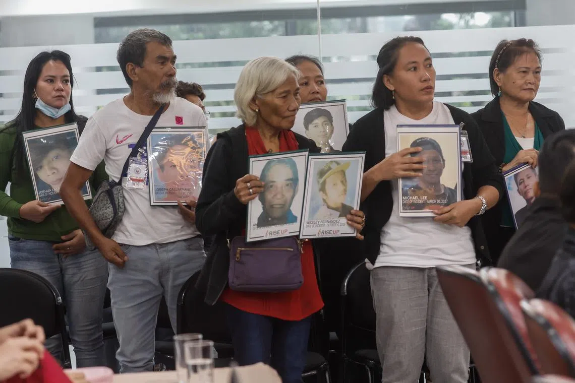 Surviving relatives hold portraits of victims of alleged extrajudicial killings during a committee hearing at the House of Representatives in Quezon City.