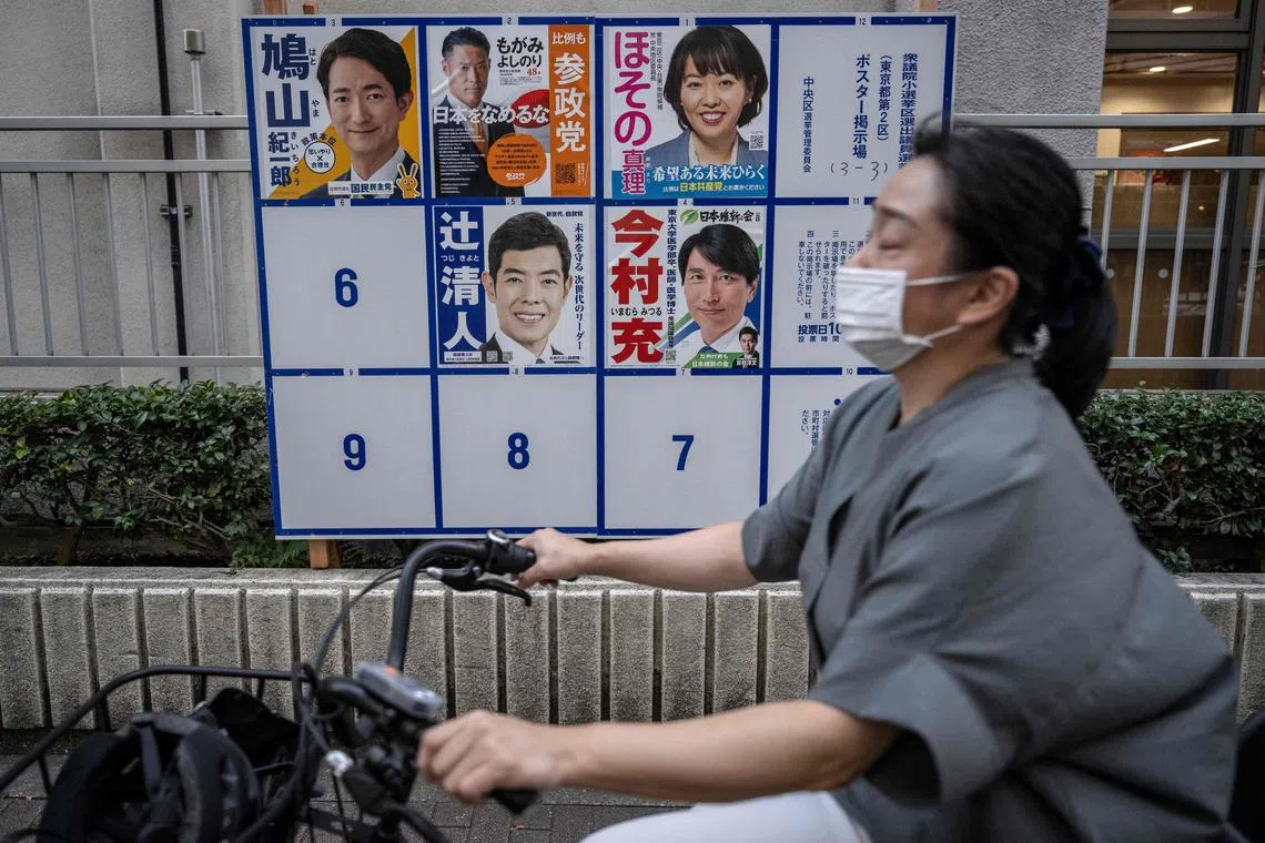 A woman cycles past campaign posters for the Tokyo No 2 seat in the Oct 27 Lower House election. Among the five candidates is Mr Kiichiro Hatoyama (top left), the son of former Prime Minister Yukio Hatoyama.
