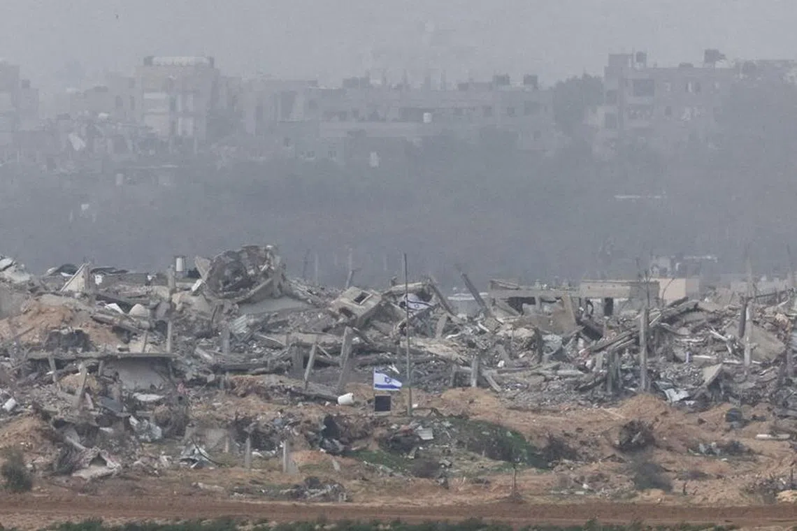 Israeli flags fly next to the rubble of destroyed buildings in Gaza on Dec 23, 2023. 
