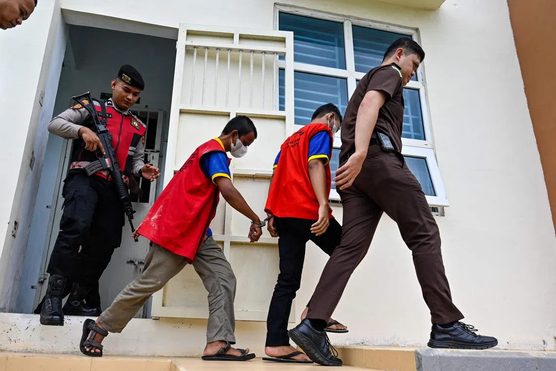 Two Indonesian men (in red vests) arrive for their hearing at a Sharia court in Banda Aceh on August 11, 2025, where they were sentenced to be flogged, each receiving 80 lashes respectively, for having gay sex which is outlawed under local Islamic law. (Photo by CHAIDEER MAHYUDDIN / AFP)