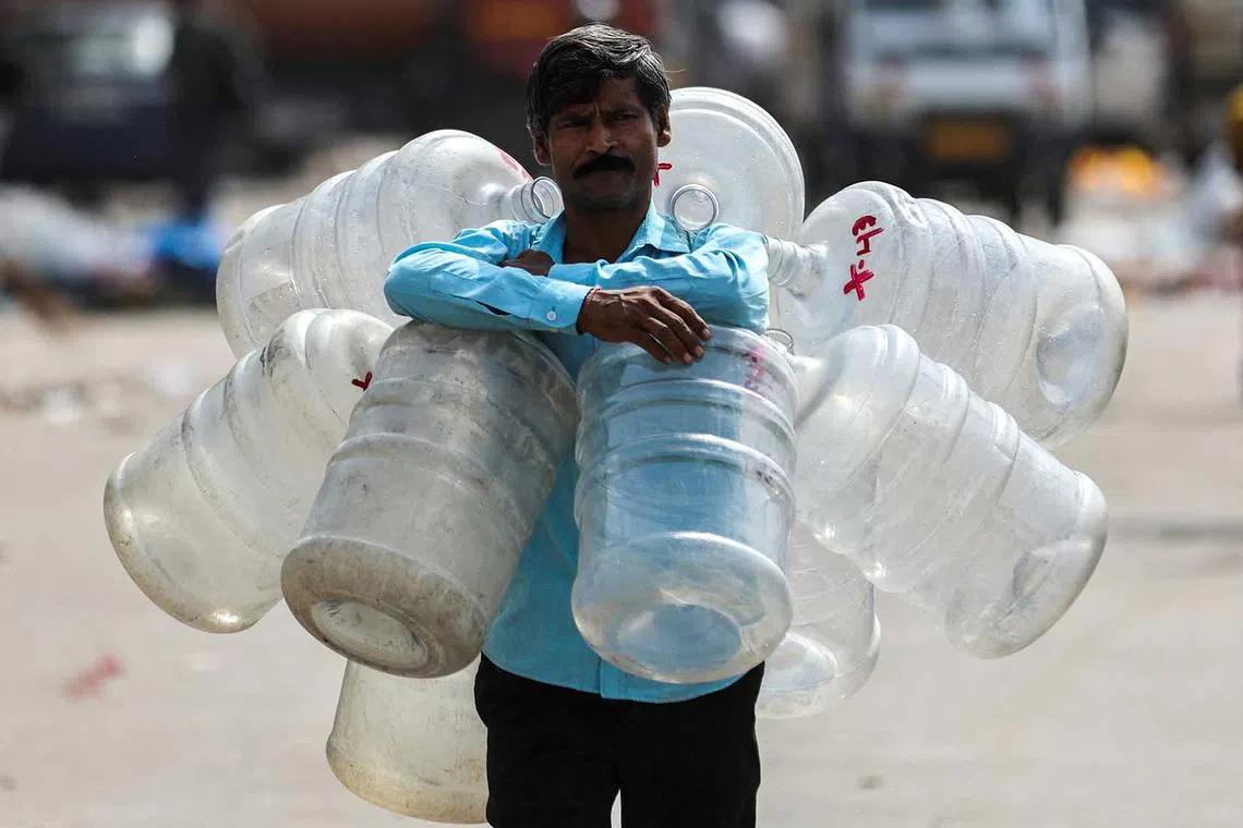 A man walks with empty water bottles around his neck to fill water to be sold for drinking in New Delhi, India, May 18.