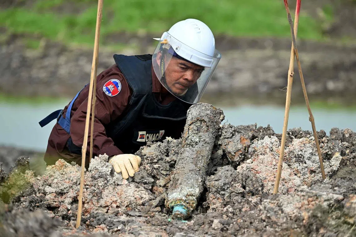Esta foto tirada em 11 de fevereiro de 2025 mostra um desmame do Centro de Ação da Mina Camboja (CMAC) examinando uma material não explodido (UXO) que foi desenterrado por um trabalhador durante o trabalho de irrigação na província de Svay Rieng. Partes do Camboja ainda estão repletas de munições não explodidas de décadas de conflito, e a decisão do presidente dos EUA, Donald Trump, de congelar praticamente toda a ajuda americana, viu muitos projetos de longa duração para limpar os detritos mortais mudarem. (Foto de Tang Chhin Sothy / AFP) / Aceitar com 'Camboja-us-Politics-Landmine-Aid, Focus', de Suy Se