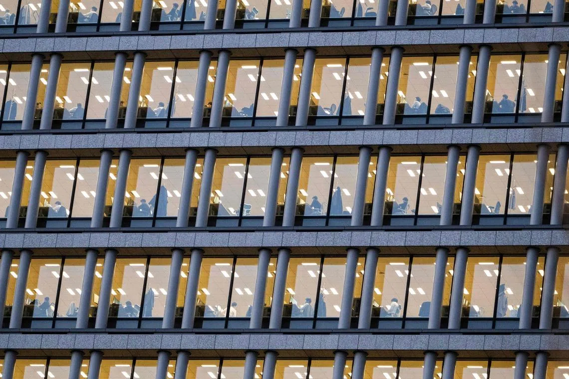 Corporate employees are seen at their desks in an office building in downtown Tokyo's Chiyoda area on March 23.