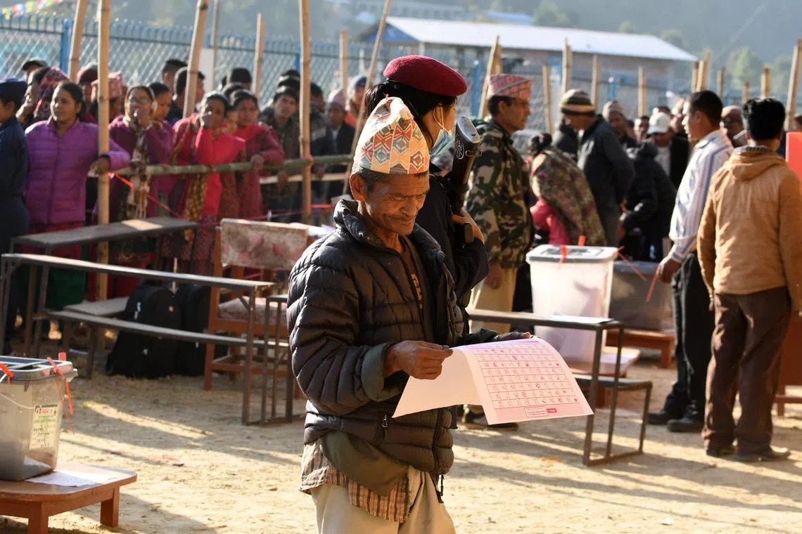 A Nepali voter examines a ballot papers before casting his vote at Chautara, Nepal, on Nov 26, 2017.