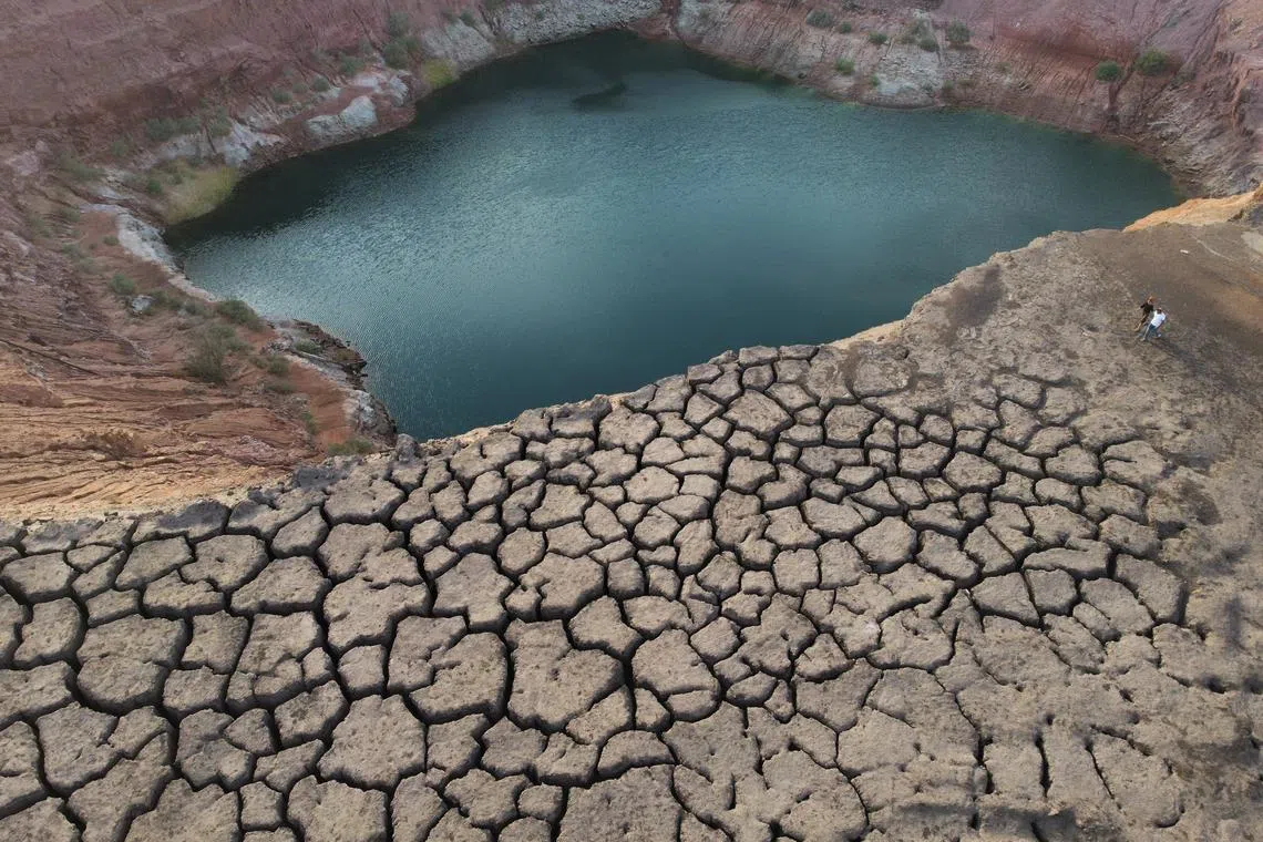 People walking on a dry cliff in an abandoned quarry near Timna Park outside the city of Eilat, Israel, on April 16, 2024. After the closure of the Timna copper mine in the 1980s, one of the quarries was flooded with groundwater, creating a huge lake.  