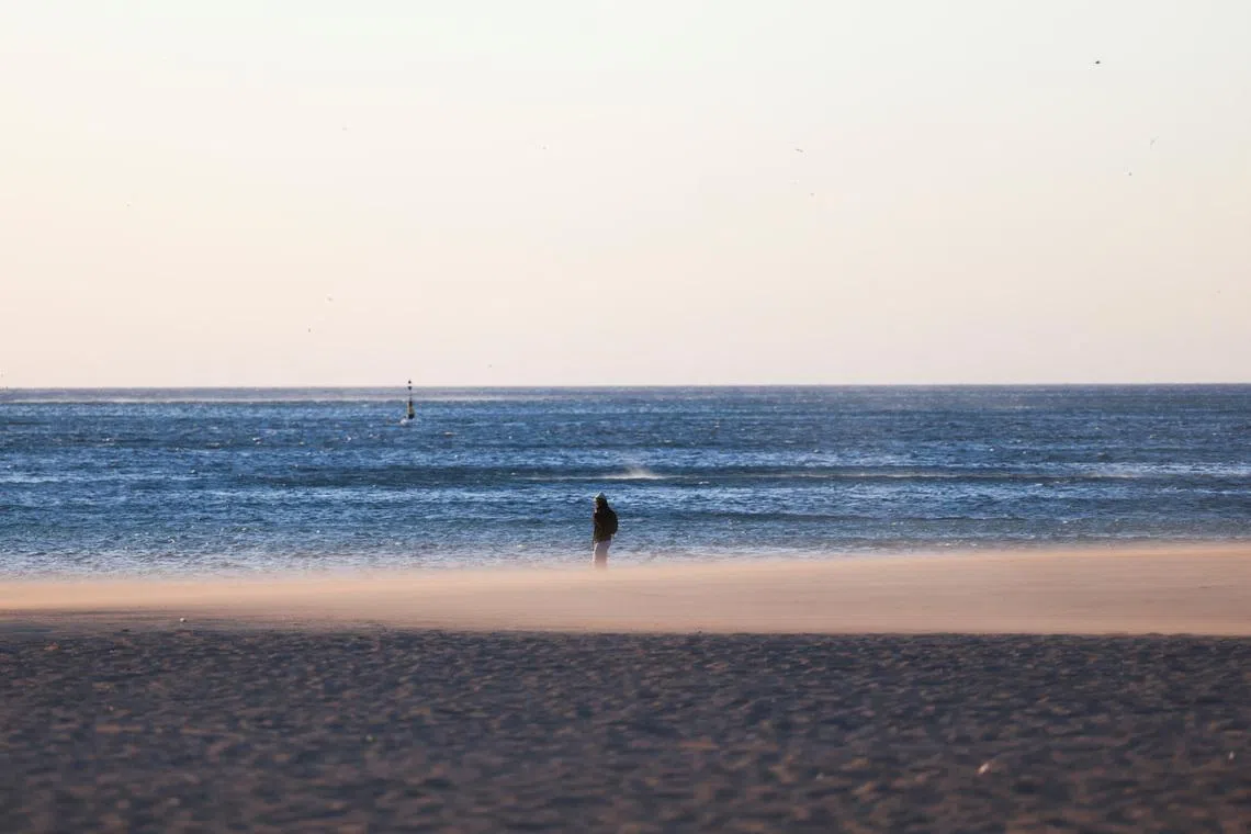 A woman walks on the Barceloneta beach during high winds in Barcelona, Spain, February 12, 2026. REUTERS/Nacho Doce