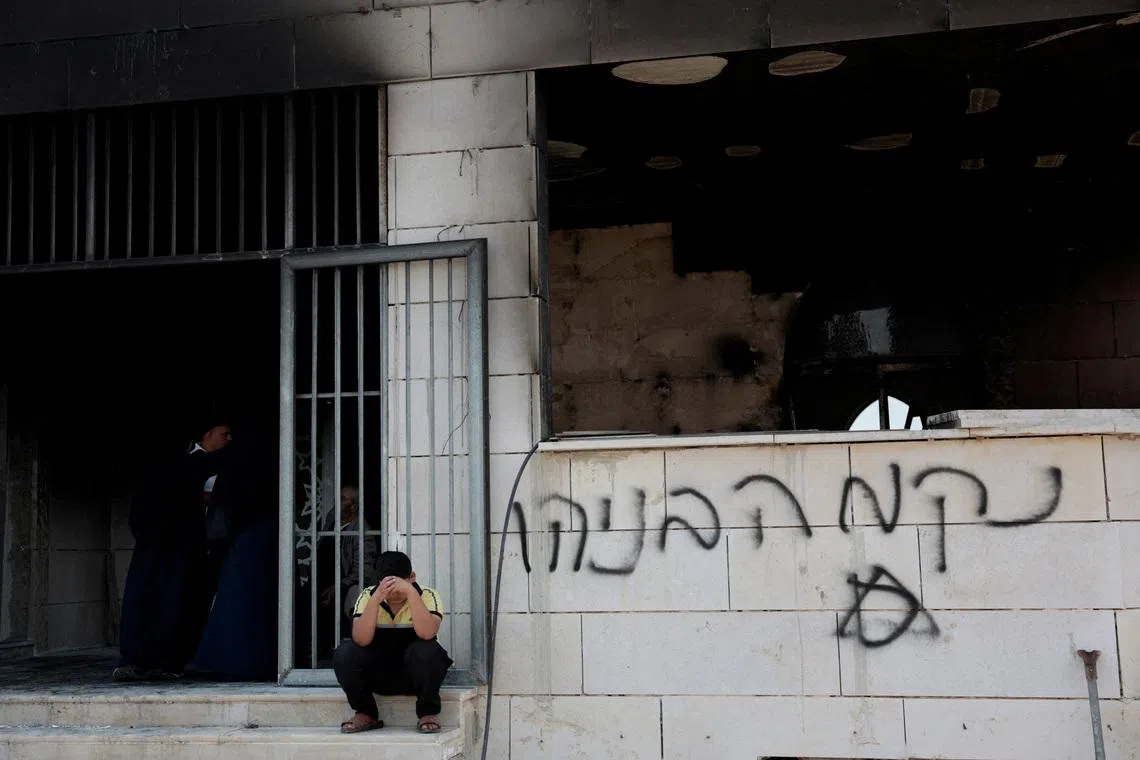 A boy sits near a damaged mosque, which Palestinians say was damaged by Israeli settlers, in West Bank on July 26.