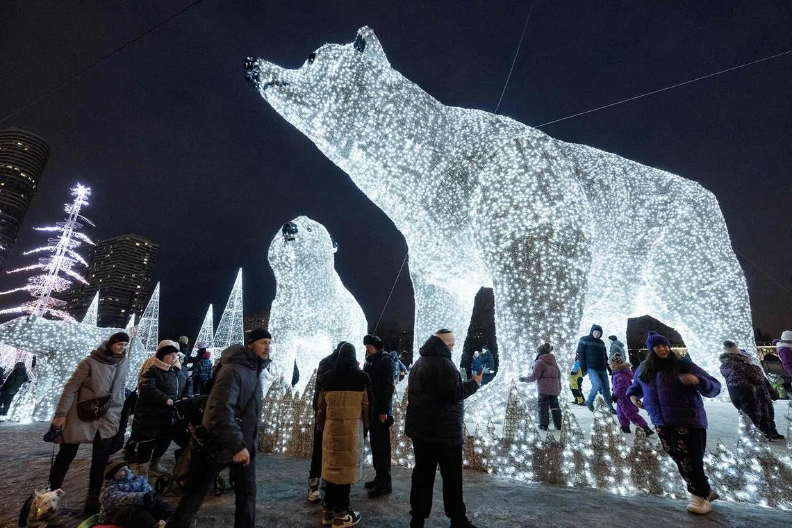 People walking in front of light sculptures of polar bears set up for the upcoming Christmas holidays in Moscow on Jan 6, 2025. Russians are preparing to celebrate Christmas, observed on Jan 7, according to the Russian Orthodox Julian calendar. 