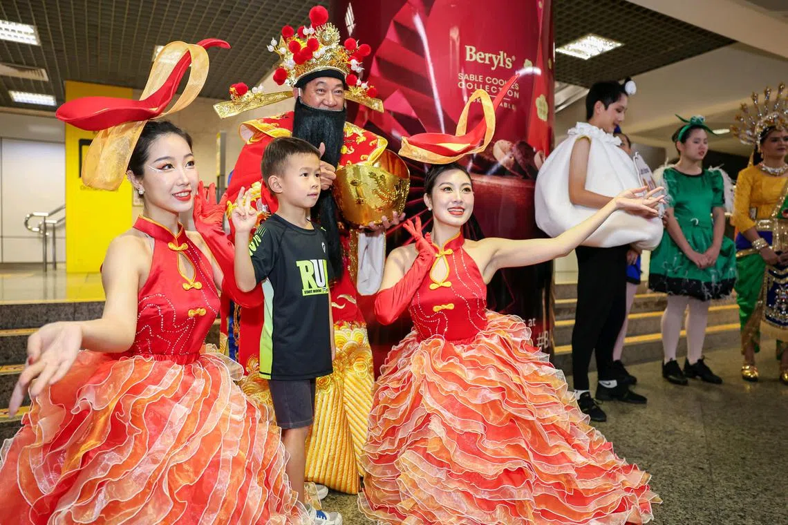 ST20250119_202561000483/occhingay19/Brian Teo/Osmond Chia Quan En/Chingay performers posing for a photo with a child during the preview parade at Orchard MRT on Jan 19, 2025. As part of the preview parade, performers went to three MRT stations - Orchard, City Hall, and Bayfront. ST PHOTO: BRIAN TEO