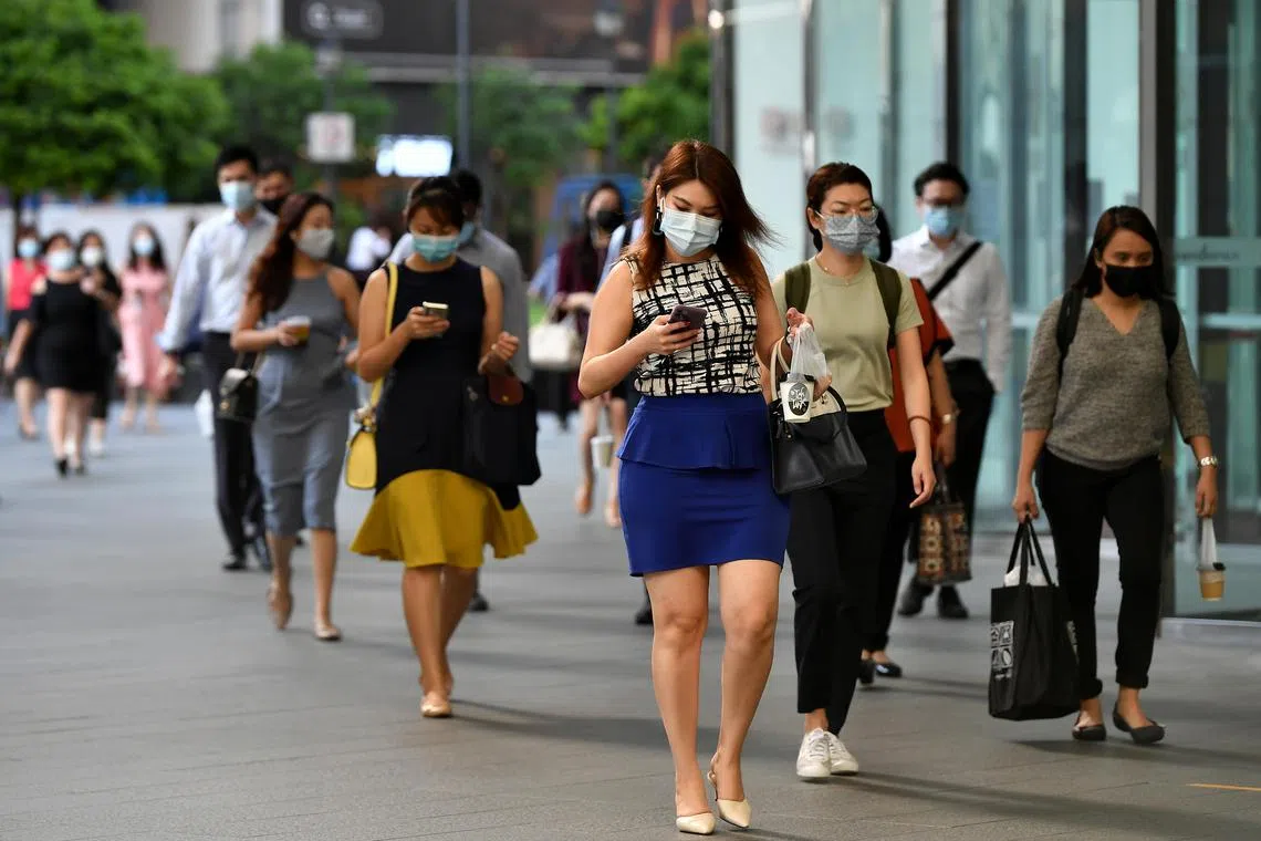Office workers wearing face masks walking to work at Raffles Place within the heart of Singapore's financial centre in the CBD area at 9am on May 11, 2021.