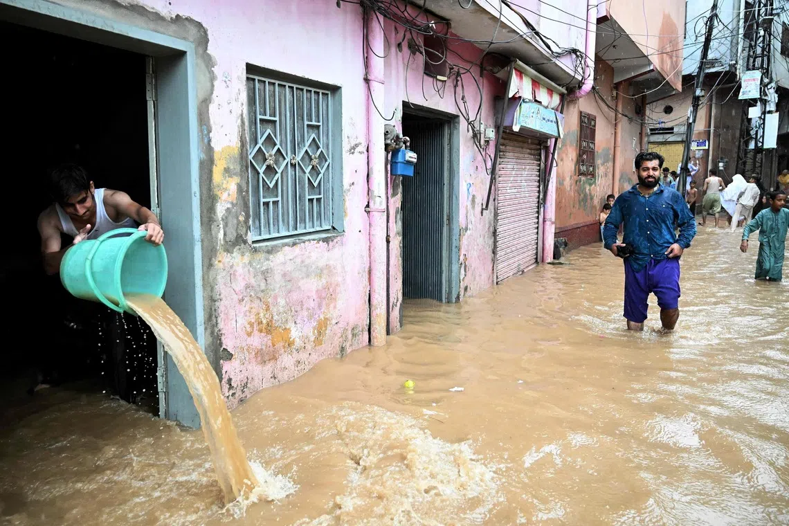 TOPSHOT - A resident removes floodwater from his home following heavy rains in Rawalpindi on August 19, 2026. (Photo by Aamir QURESHI / AFP)