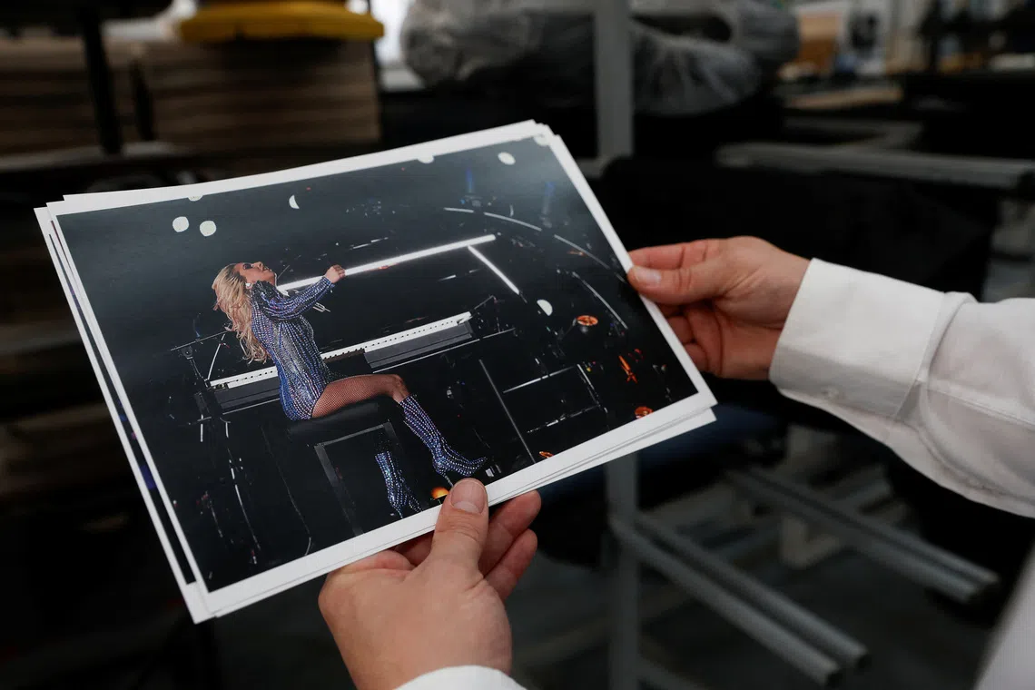 Raul Romera, 47, manager of Hidrau, a company that was devastated by the floods of 2024 and has just resumed operations, holds a photograph showing Lady Gaga sitting during the Super Bowl on one of the piano benches manufactured by the company, in Algemesi, near Valencia, Spain, October 24, 2025. REUTERS/Eva Manez