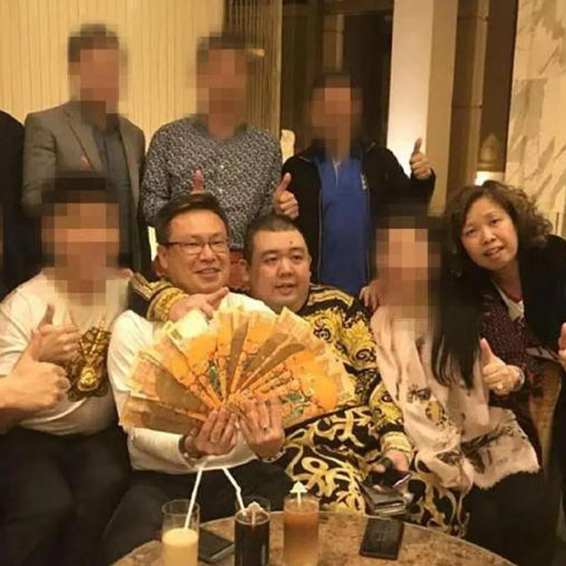Mr Wan Hoe Keet (holding cash) and his wife Sally Ho, seen here with Mr Peter Ong, at a 2018 meeting in Macau.