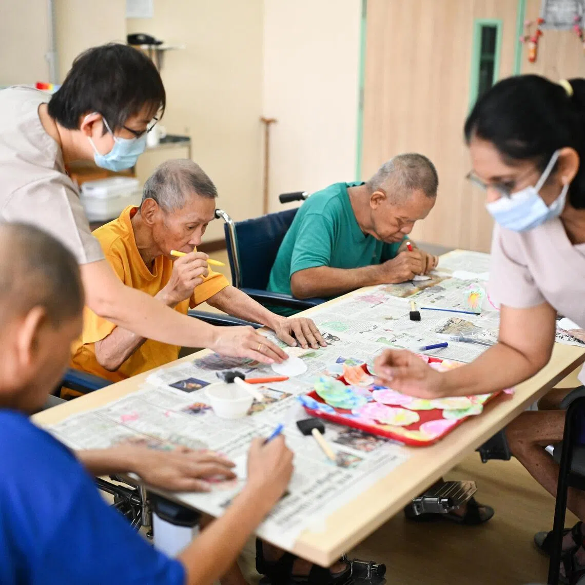 St Andrew's Nursing Home (Buangkok) residents doing cognitive art and craft with therapy assistants Kelly Poh (standing, left) and Rekha Chandran.