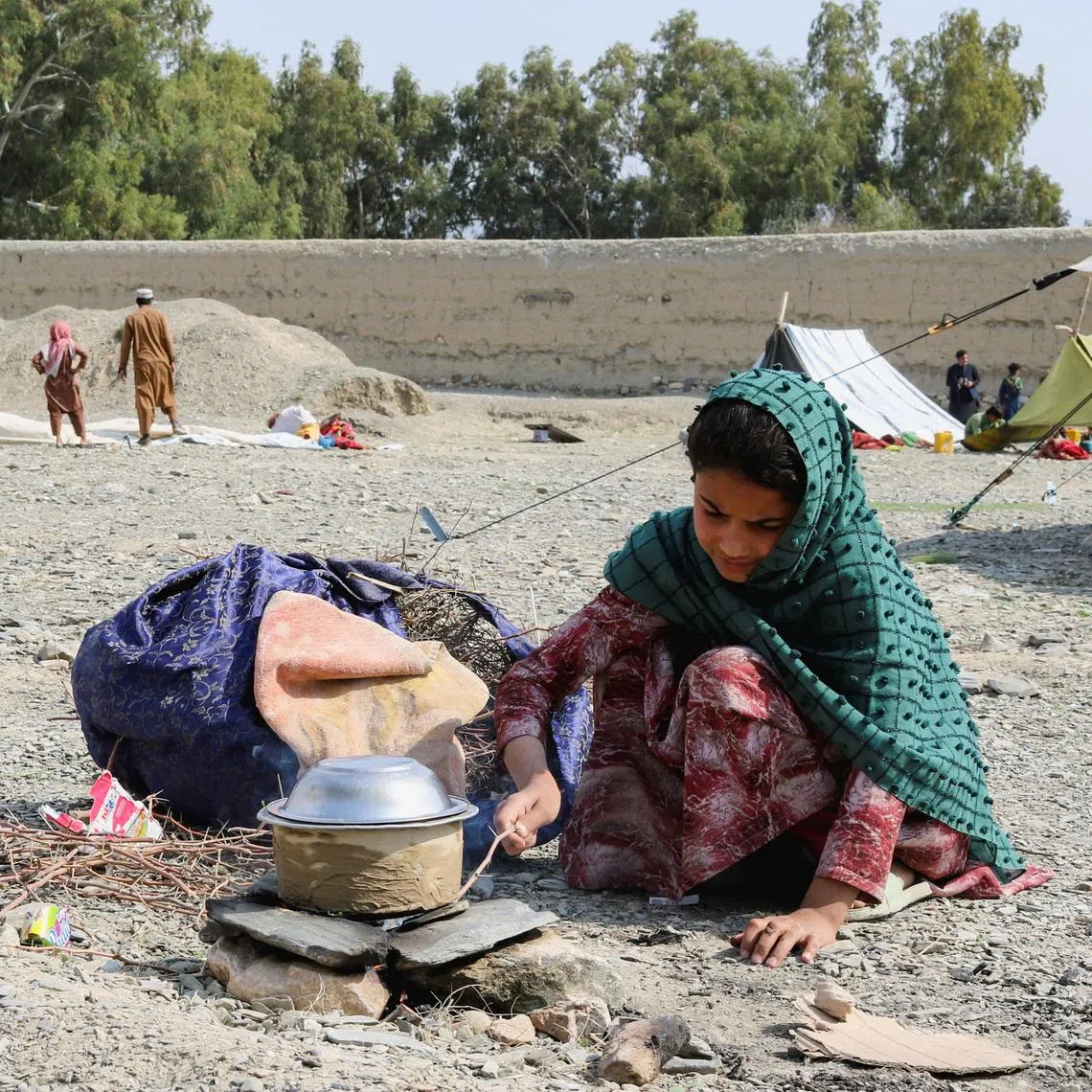 An Afghan girl cooks on a rock stove outside her family's tent as they take refuge in Lal Pur district in Afghanistan on March 4.
