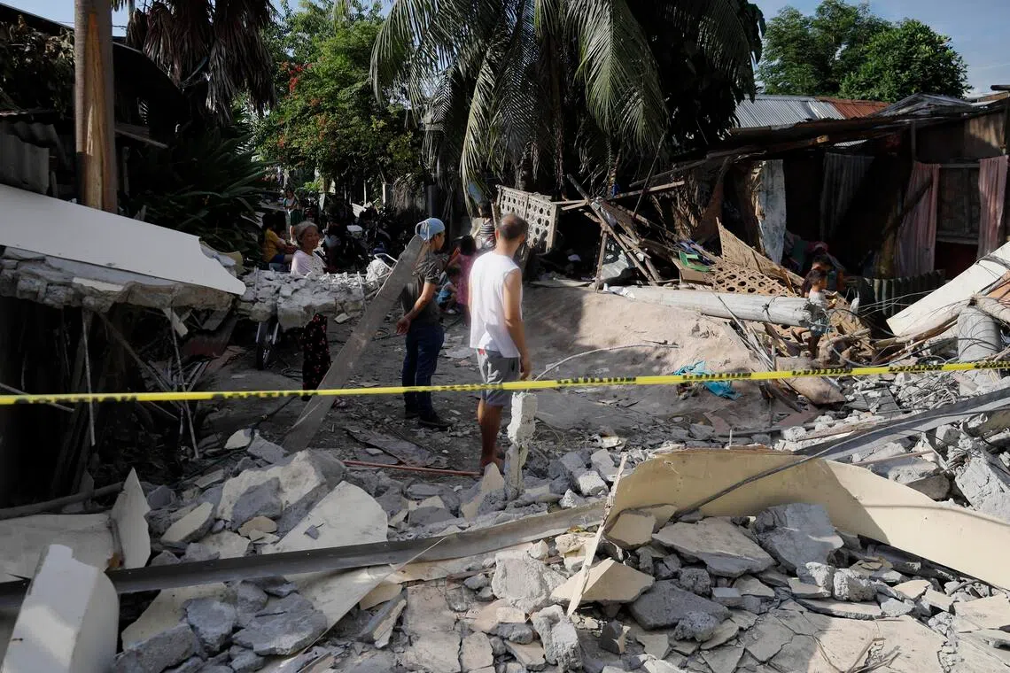People inspect the damage at the site of a collapsed wall separating a warehouse-type facility and several homes, a day after an earthquake, in General Santos City, southern Philippines, on June 9.