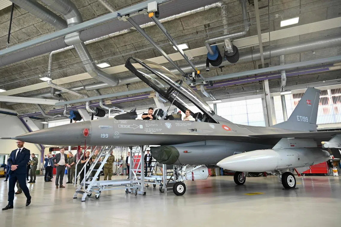 Ukrainian President Volodymyr Zelensky (left) and Danish Prime Minister Mette Frederiksen sit in a F-16 fighter jet, in Denmark.