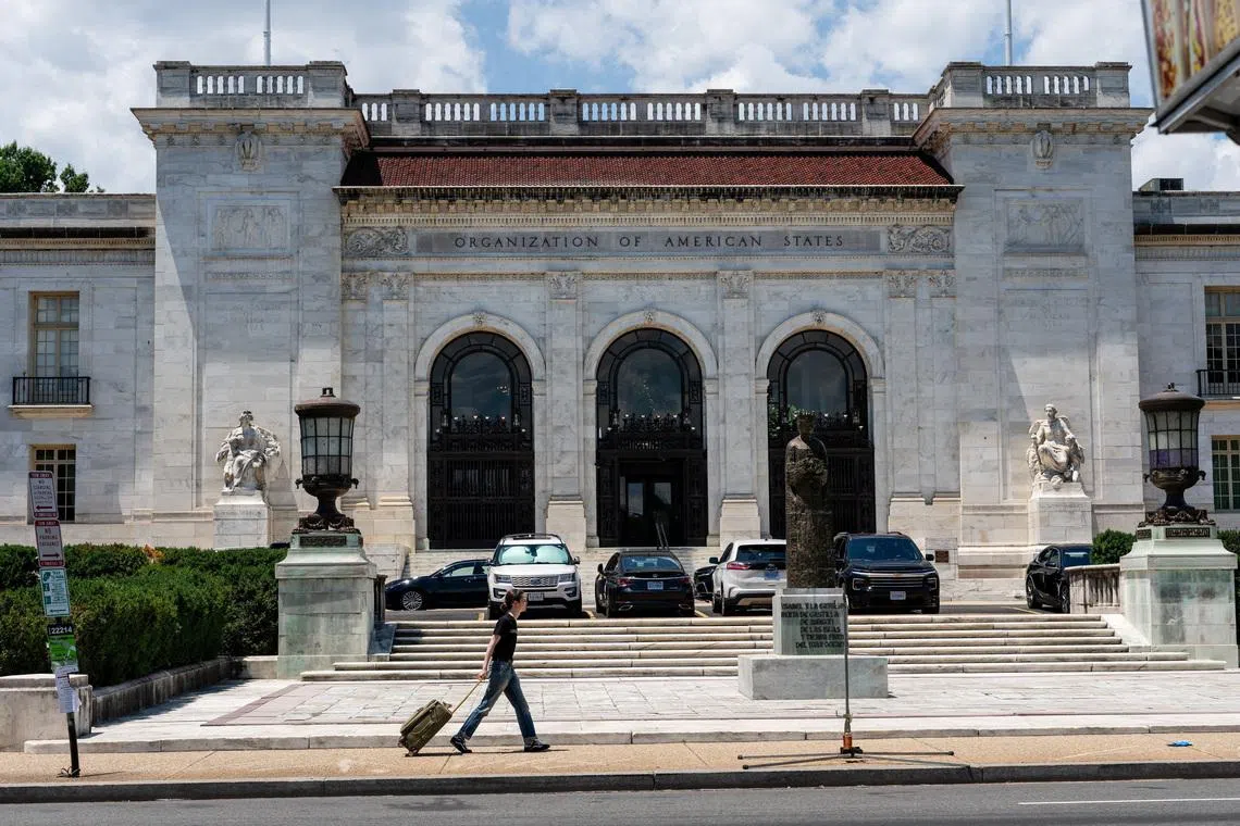 A person pulls a rolling suitcase as they walk by the Organization of American States (OAS) headquarters in Washington, D.C., U.S., June 17, 2026. REUTERS/Eric Lee