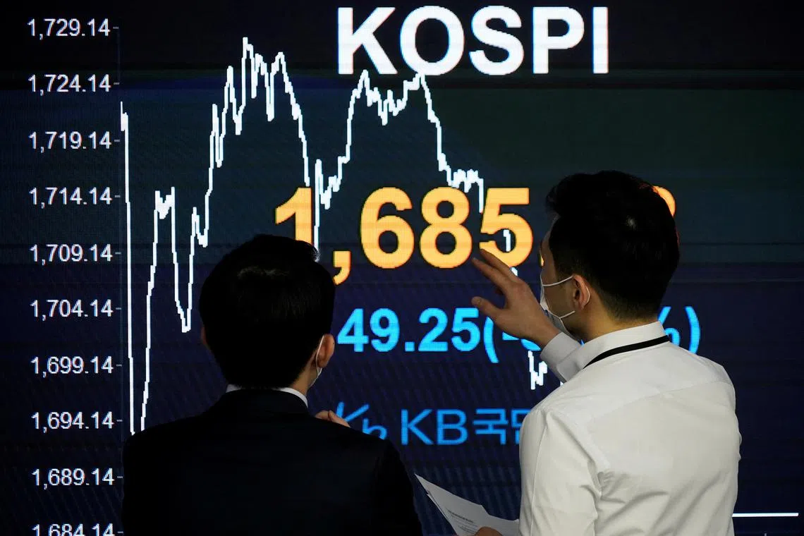 FILE PHOTO: Currency dealers talk in front of an electronic board showing the Korea Composite Stock Price Index (KOSPI) at a dealing room of a bank in Seoul, South Korea, March 13, 2020.   REUTERS/Kim Hong-Ji/File Photo