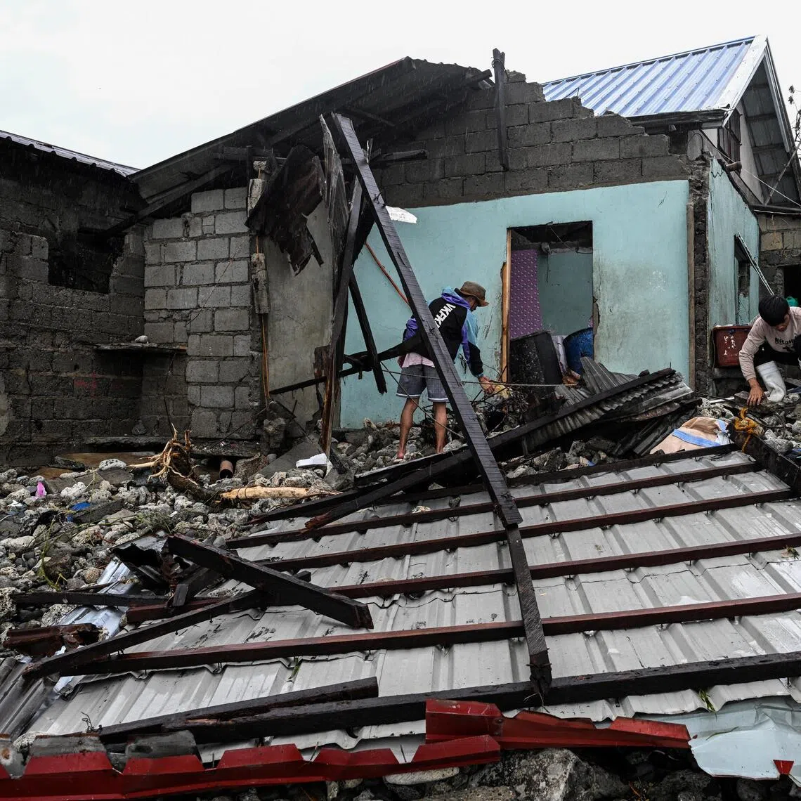 Men look for belongings in front of their house damaged by storm surges after Typhoon Fung-wong hit the coast of Alacan, Pangasinan, Philippines, on Nov 11.