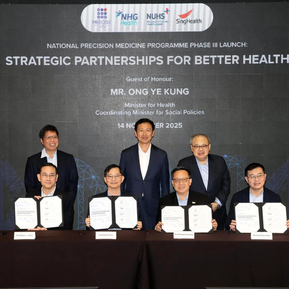 CMG20251114-TayYM02/郑一鸣 /卢慧菁，郭跃男 /National Precision Medicine
Programme Phase Ill Launch:
Strategic Partnerships for
Better Health [Marina One Auditorium,
Level 3]

图说：社会政策统筹部长兼卫生部长王乙康（后排中），见证新加坡精准健康研究所执行董事陈文炜教授（前排左二）与三大公共医疗集群代表签署谅解备忘录，象征全国精准医学计划正式迈入第三阶段。前排左一为国立健保集团医疗委员会主席 (医学研究)薛寒友教授；前排右一起为新保集团副总裁（研究、教育与创新）林顺泰教授及国立大学医学组织副首席执行官 （教育与研究）钟业成教授。