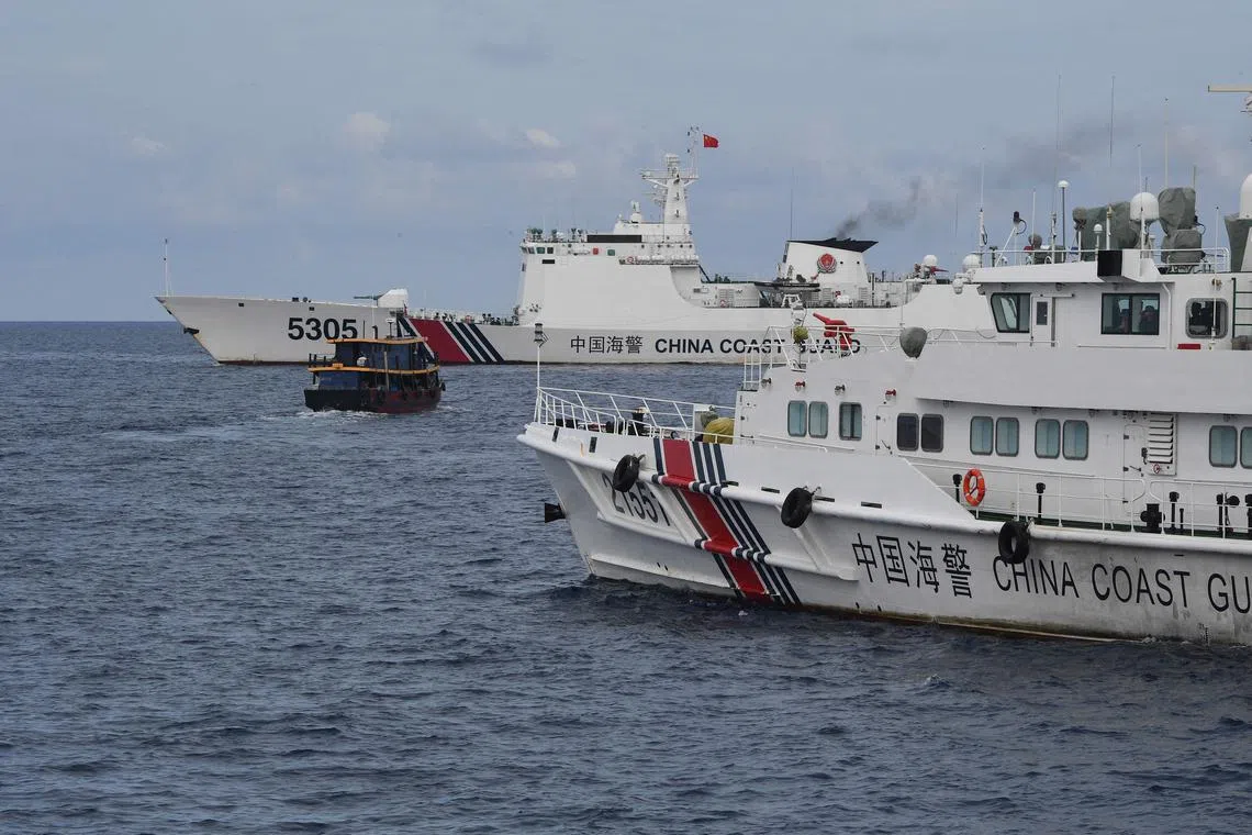 Two Chinese coast guard ships are seen in this photo corralling a civilian boat chartered by the Philippine Navy to deliver supplies to an outpost in the disputed South China Sea. 