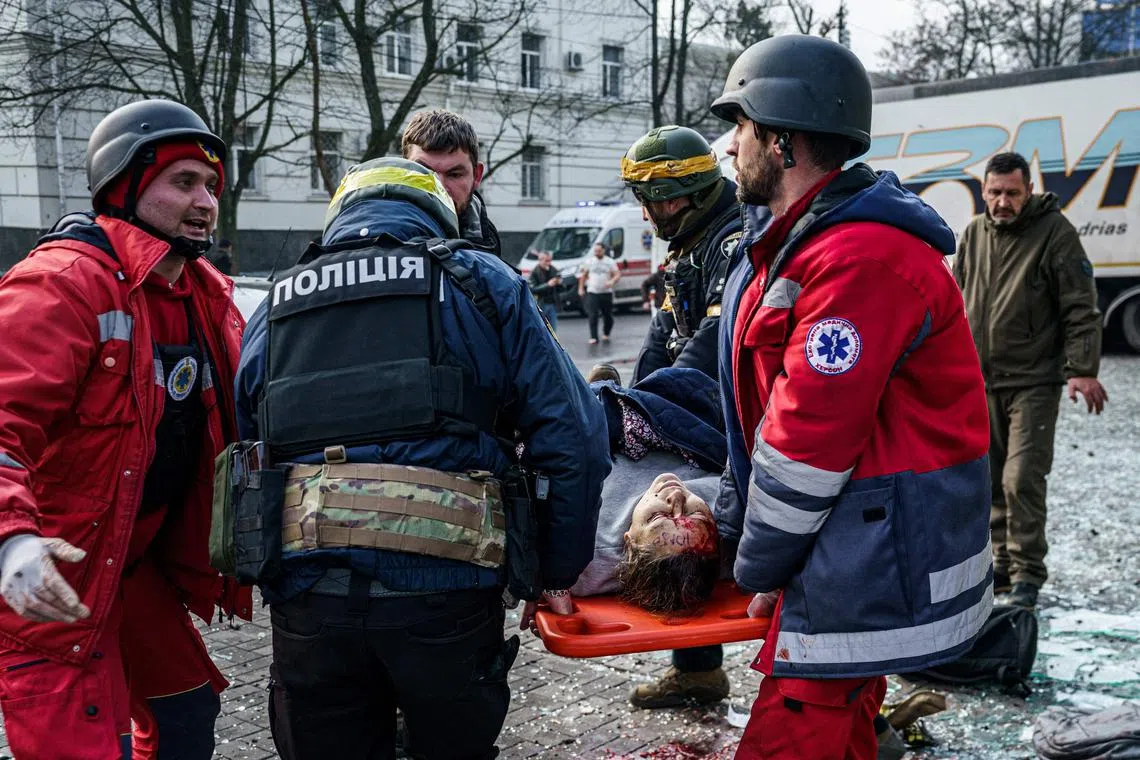 Rescuers carry an injured woman on a stretcher following Russian shelling on the Ukrainian city of Kherson on Dec 24, 2022.