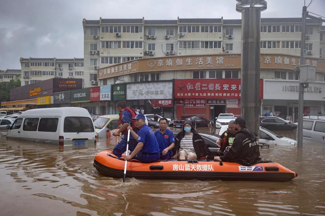 Rescue workers in a boat go through a flooded street in Beijing on Aug 1, 2023.
