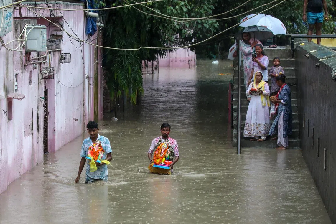 epa12346511 Indian people carry the idols of the elephant-headed Hindu god Ganesha for immersion as part of the Ganesh Chaturthi festival, through flood water from the swollen Yamuna River at Yamuna Bazar in New Delhi, India, 02 September 2025. The Yamuna river crossed the danger mark after heavy rainfall in Delhi, and the government issued warnings over flood-like conditions, asking residents living on the river bed or in low-lying areas to evacuate to temporary shelters.  EPA/RAJAT GUPTA