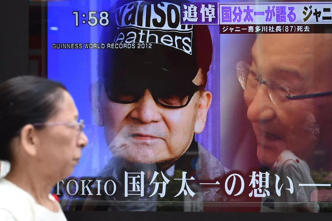 In this file photo, a woman walks past a roadside television screen reporting the death of Johnny Kitagawa, founder of Japanese talent agency Johnny & Associates, in Tokyo on July 10, 2019.