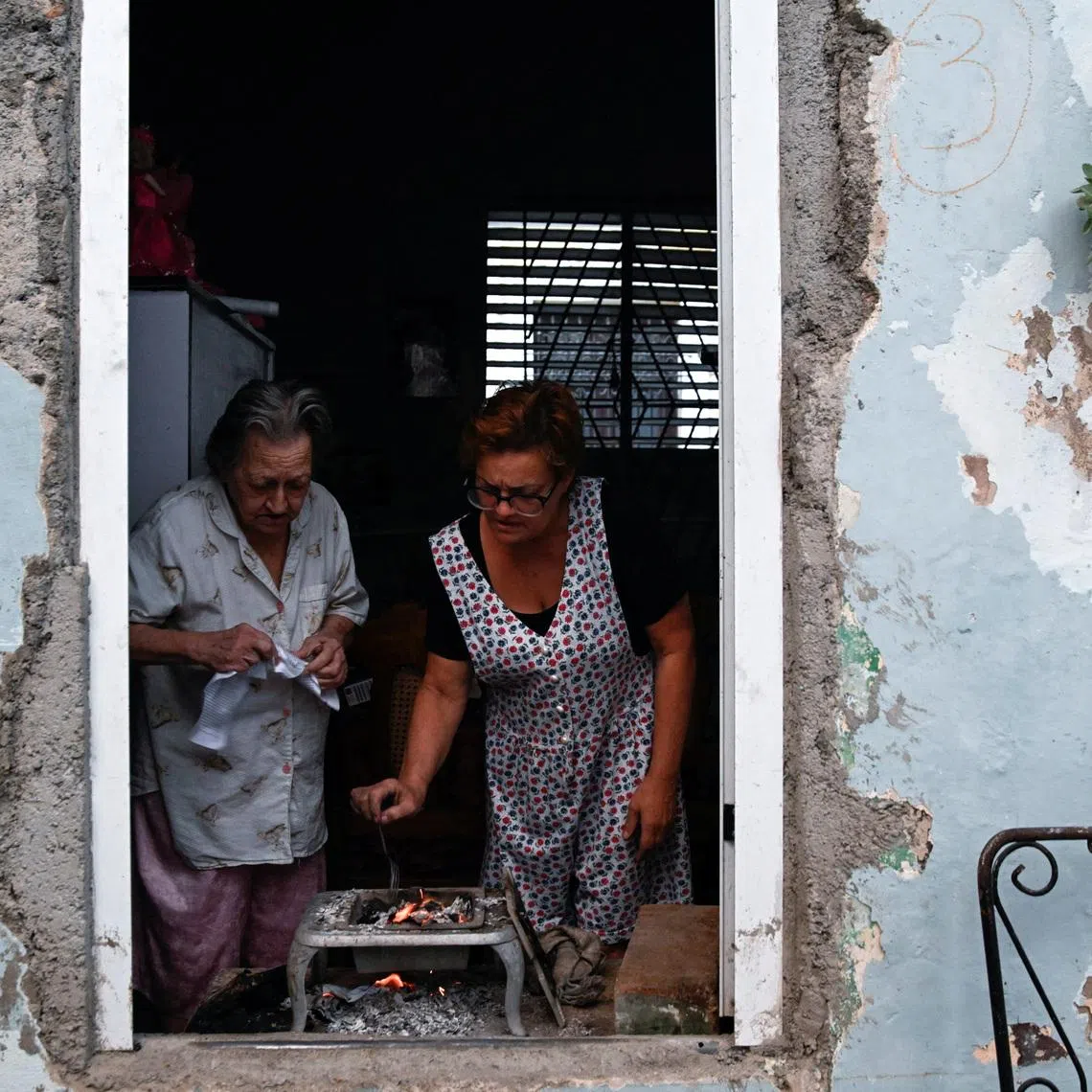 Mirna Clavijo, 84, and her daughter Isabel Gutierrez, 61, cook dinner as Cuba's national electric grid collapsed for the second time in a week amid the U.S.-imposed oil blockade, according to officials, as the communist government struggles to keep the lights on for about 10 million people with decrepit infrastructure, in Havana, Cuba, March 21, 2026. REUTERS/Norlys Perez