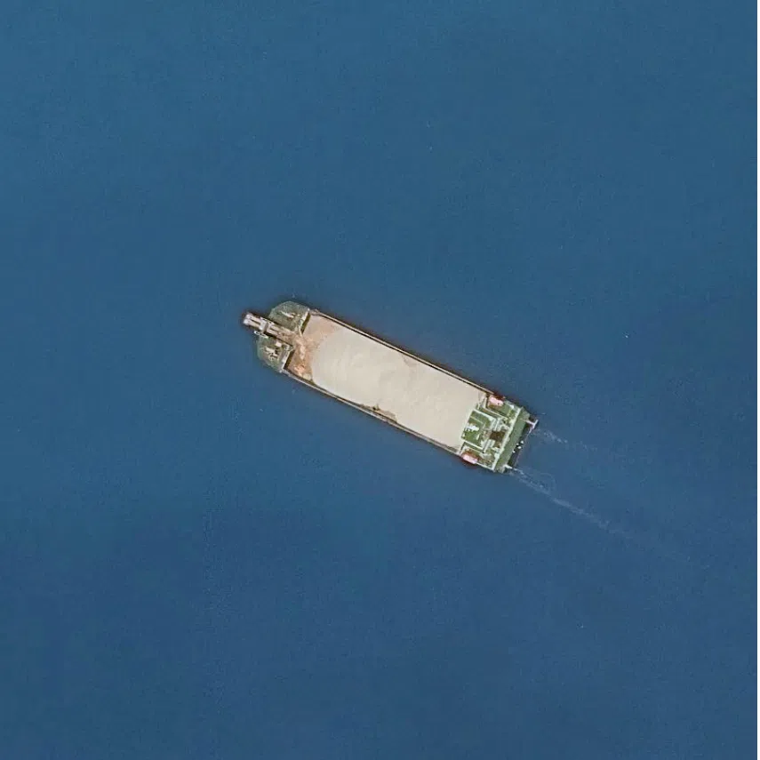 A satellite view of dynamic compaction (left) and a gravel-loaded barge (right) at Antelope Reef in the South China Sea on Sept 25.