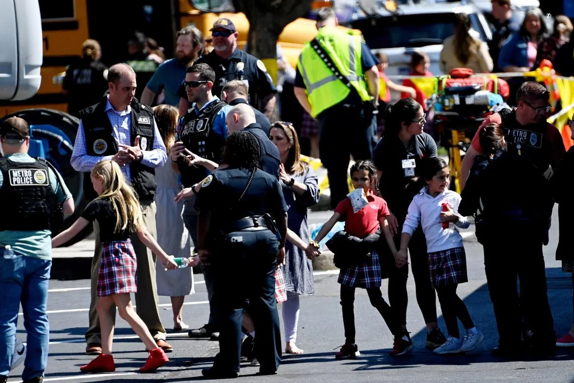 Students from the Covenant School hold hands after getting off a bus to meet their parents following a mass shooting at the school on March 27, 2023. 