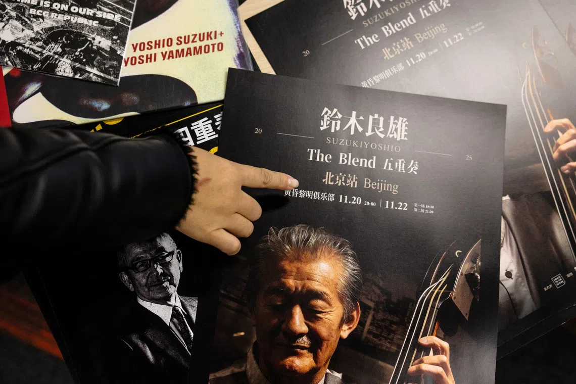 A woman points to an advertisement poster for a cancelled concert by Japanese musician Yoshio Suzuki before the organisers' interview with Reuters in Beijing, China, November 21, 2025. REUTERS/Maxim Shemetov