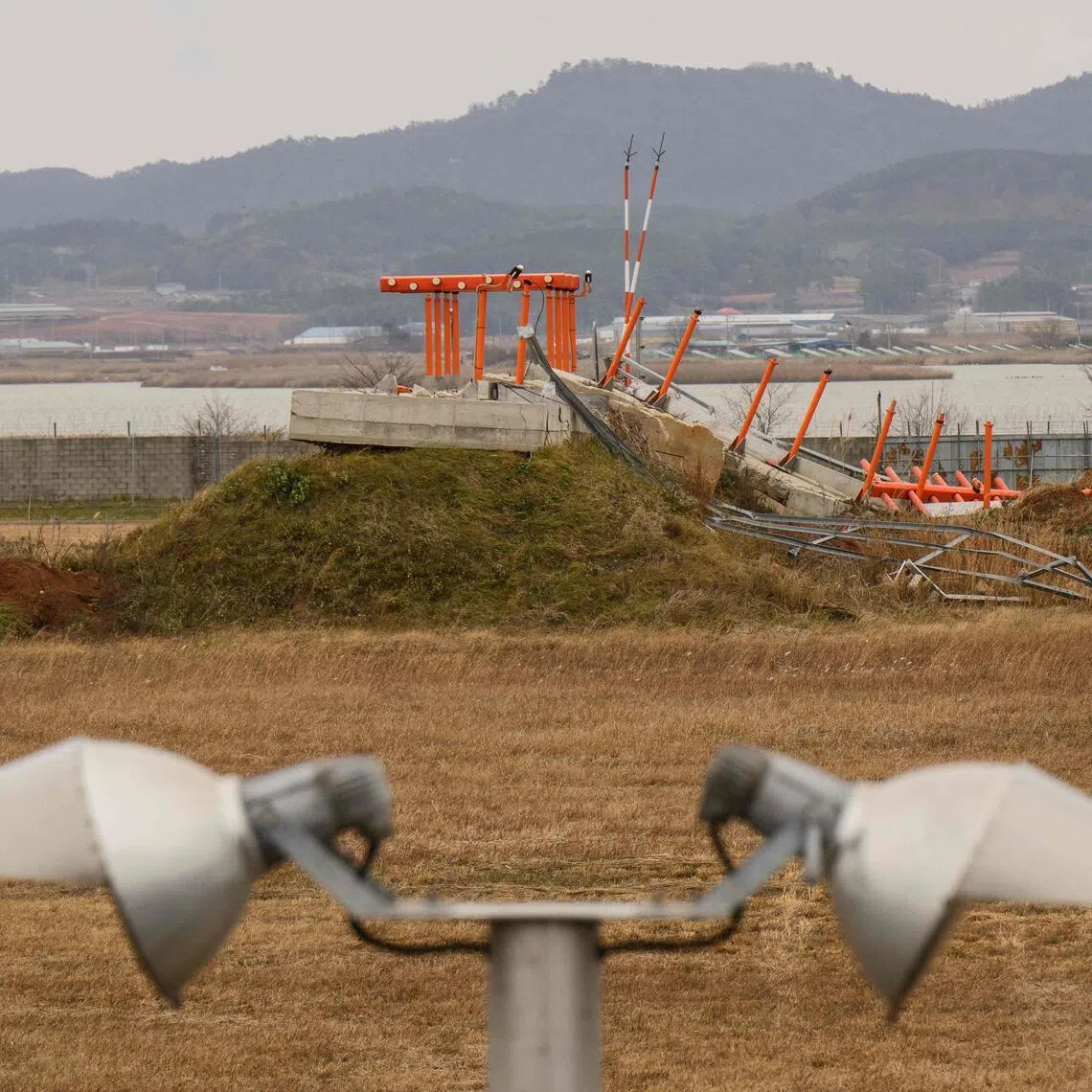 A damaged structure is seen at the end of the runway at Muan International Airport.