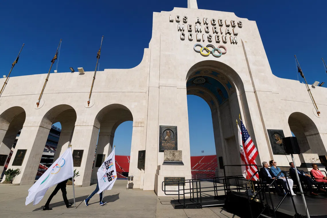 FILE PHOTO: LA28 workers carry Olympic flags on the day of a ceremony to announce the locations for the opening and closing of the Olympic and Paralympic games, in Los Angeles, California, U.S., May 8, 2025.   REUTERS/Mike Blake/ File Photo