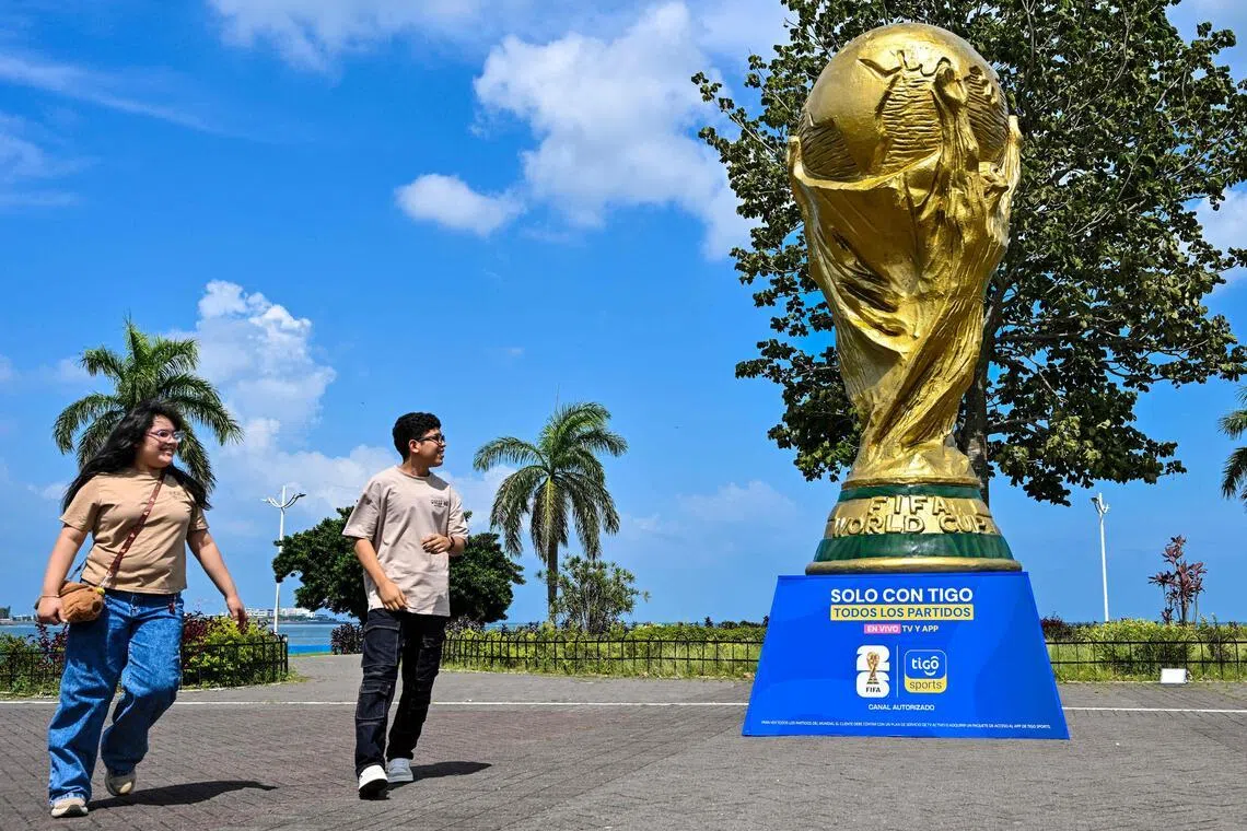 People walk past a giant replica of the FIFA World Cup trophy at the Cinta Costera in Panama City on May 13, 2026.