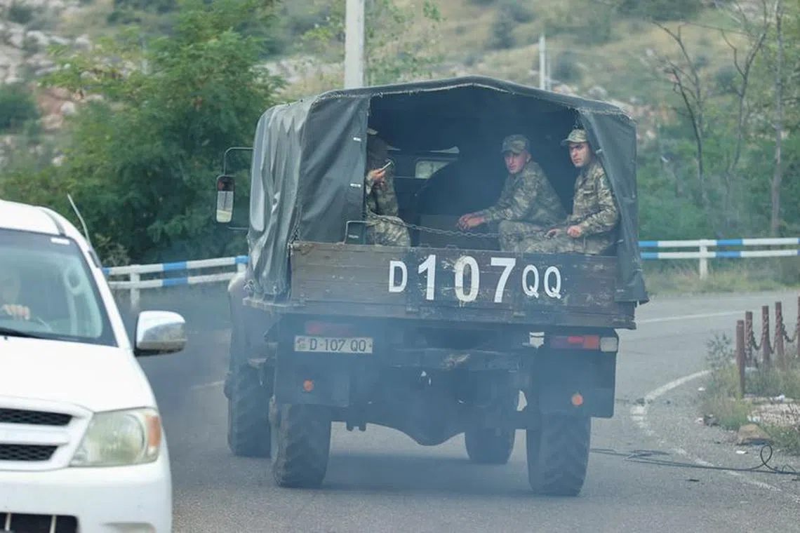 A view through a car window shows Azerbaijani service members riding in the back of a truck in Stepanakert city, known as Khankendi by Azerbaijan, following an Azeri military operation and a further mass exodus of ethnic Armenians from the region of Nagorno-Karabakh, October 2, 2023. REUTERS/Aziz Karimov/File Photo