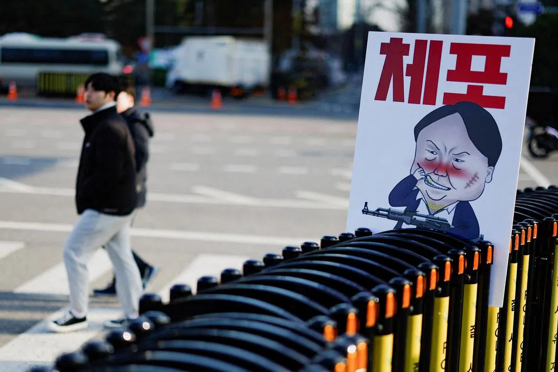 A pedestrian walks past a banner denouncing South Korean President Yoon Suk Yeol, who declared martial law, which was reversed hours later, in front of the National Assembly in Seoul, South Korea, December 9, 2024. The slogan reads, 'arrest'. REUTERS/Kim Kyung-Hoon