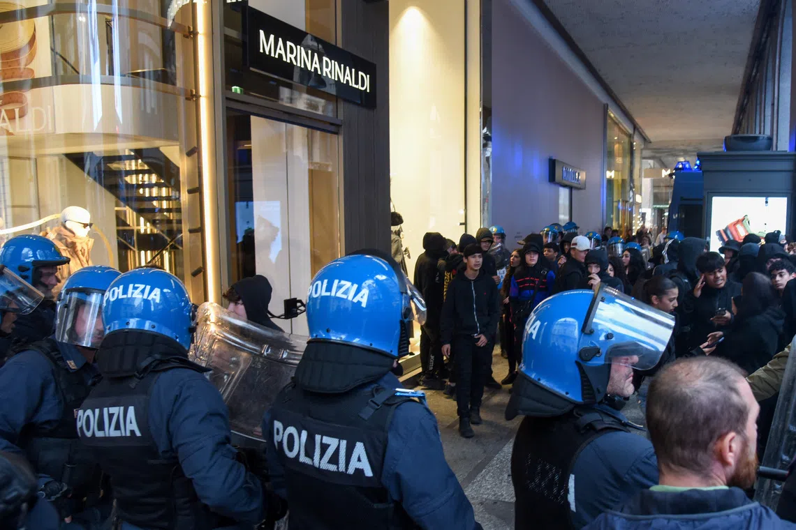 Italian police facing a crowd during a protest over the state of public services and the rising cost of living in Milan on Oct 18.