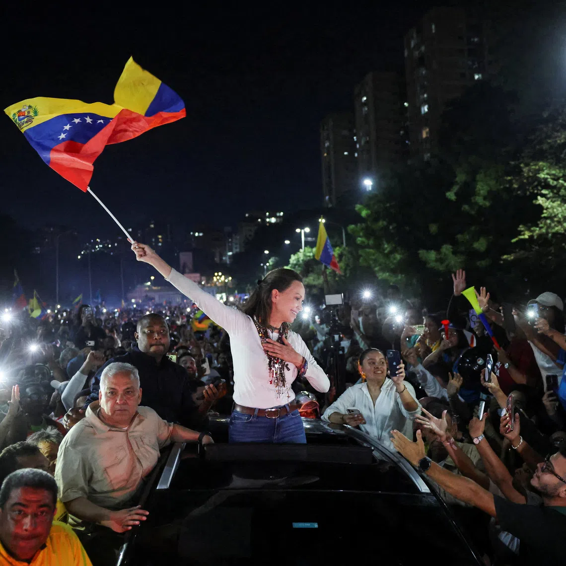Venezuelan opposition leader Maria Corina Machado waves a Venezuela flag while greeting supporters as she arrives in Caracas after travelling by road from Barquisimeto, where she made her first public appearance following her return to the country after nearly a year abroad, in Caracas, Venezuela, October 25, 2026. REUTERS/Leonardo Fernandez Viloria