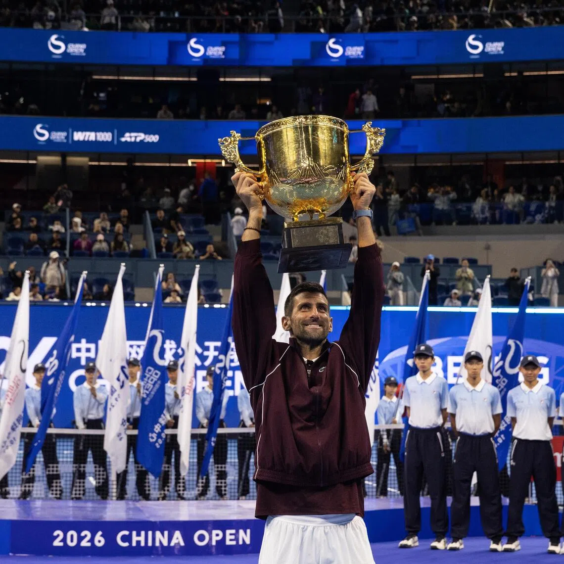 Novak Djokovic celebrating with the trophy after winning the China Open on Oct 6, following the retirement of Australia’s Alex de Minaur.