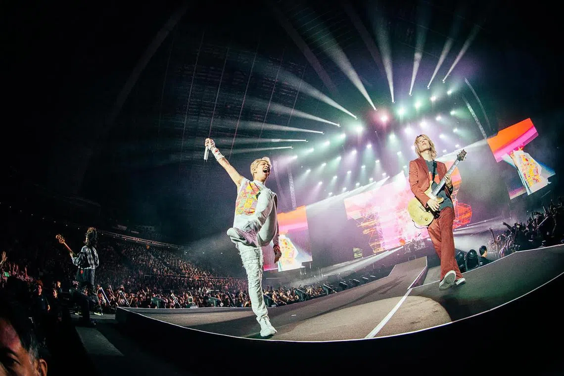 Japanese band One Ok Rock's frontman Taka (centre) and guitarist Toru (right, in red)  performing at the band's sold-out concert at the Singapore Indoor Stadium in December 2023.
