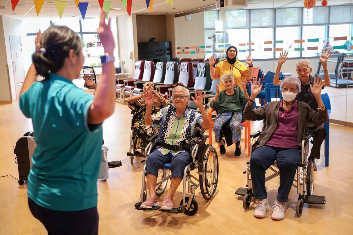 Patients at Dover Park Hospice's day care doing a volunteer-led seated exercise activity.