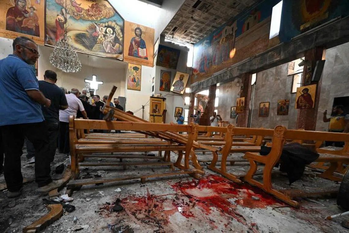 A man looks at blood stains as rescuers inspect the damage at the site of a reported suicide attack at the Saint Elias church in Damascus' Dwelaa area on June 22, 2025. Syrian state media reported a suicide attack on a Damascus church on June 22 that caused casualties, as AFP correspondents at the scene saw first responders transporting people from the site. (Photo by LOUAI BESHARA / AFP)
