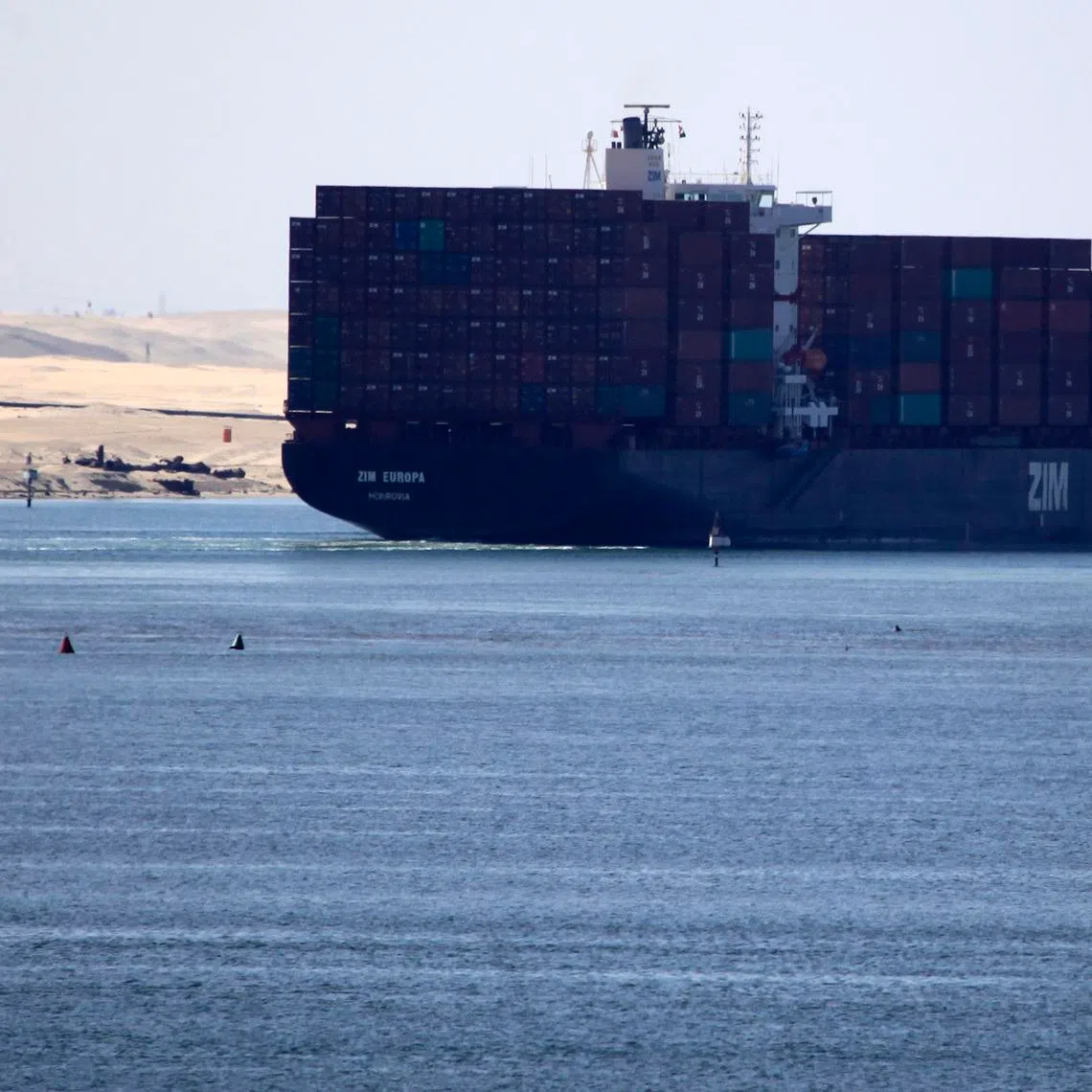 FILE PHOTO: A fisherman travels on a boat with his family in front of the Zim container ship near Ismailia port city, northeast of Cairo May 1, 2014/ File Photo