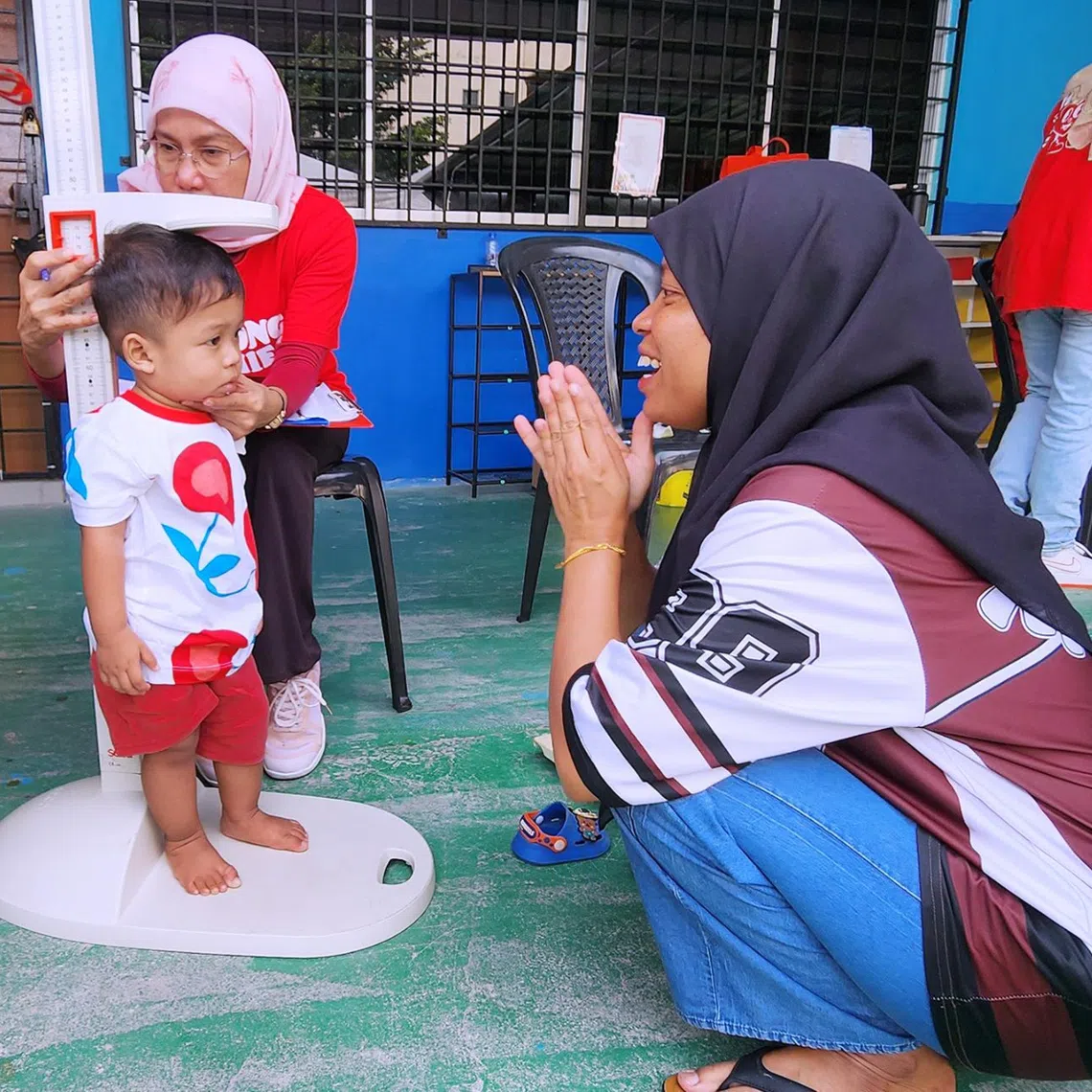Riza Halow watches as her son has his height measured during a health check at a community programme for children with growth concerns in Puchong, Selangor.