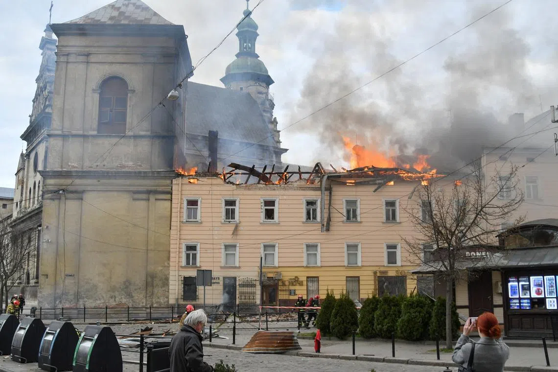 Residents look at firefighters who work at the site of a building which was hit by a Russian drone strike, amid Russia's attack on Ukraine, in the downtown of Lviv, Ukraine, March 24, 2026. REUTERS/Stringer