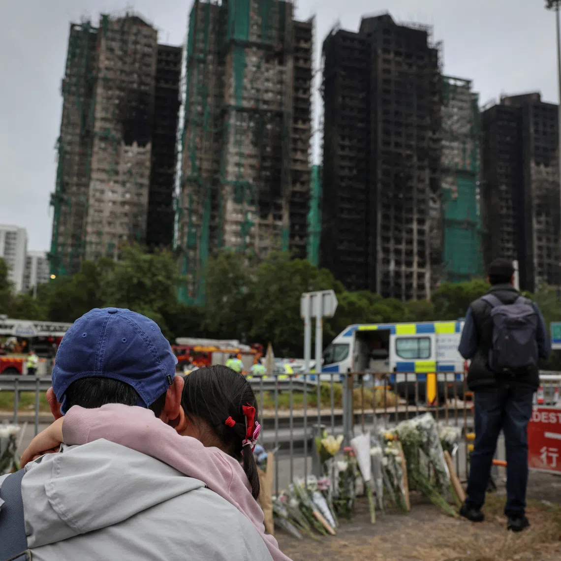People pay tribute in front of the Wang Fuk Court housing complex following the deadly fire.