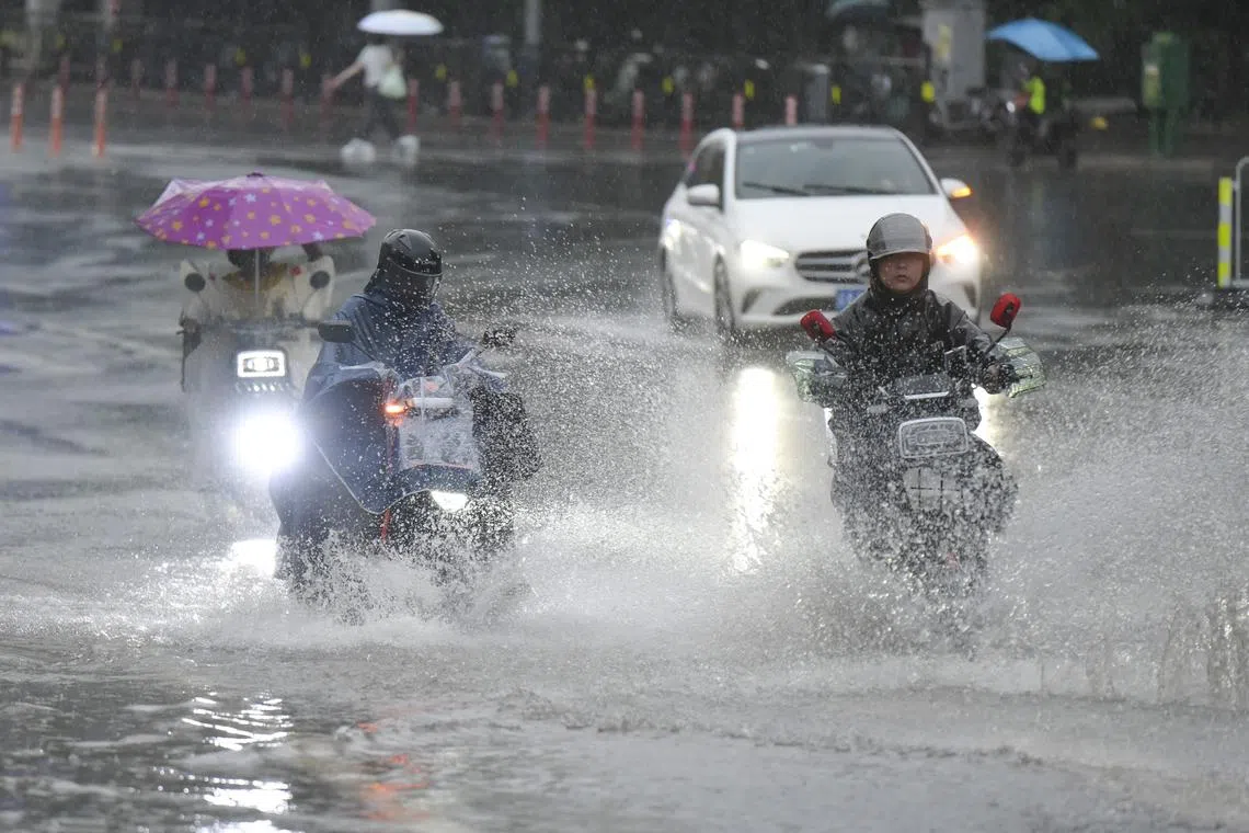 People ride on a waterlogged road in rain in Guangzhou, Guangdong Province of China, on April 20.
